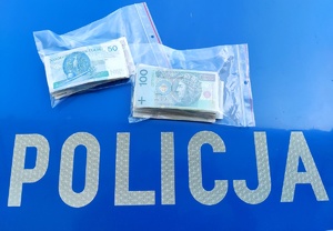 Pieniądze w woreczkach foliowych na masce radiowozu oraz napis policja