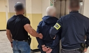 zatrzymany zakuty w kajdanki prowadzony przez dwóch policjantów