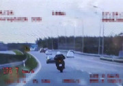 zdjęcie z nagrania wideorejestratorem. sylwetka motocyklisty jadącego drogą