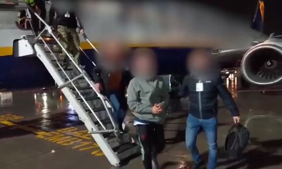 zatrzymany z policjantami schodzi po schodach z samolotu
