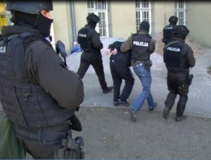 Policjanci prowadzą jednego z zatrzymanych