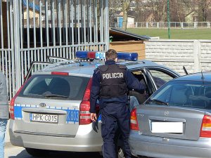 zatrzymany w radiowozie, policjant zamyka drzwi od auta
