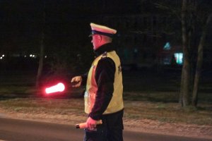 policjant nocą z latarką do zatrzymywania pojazdów