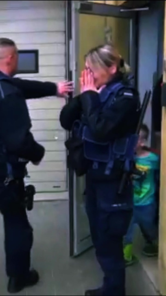 Policjantka ze wzruszenia zakrywa rękami twarz.