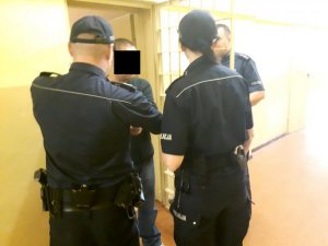 Policjanci doprowadzają do policyjnej celi jednego z zatrzymanych