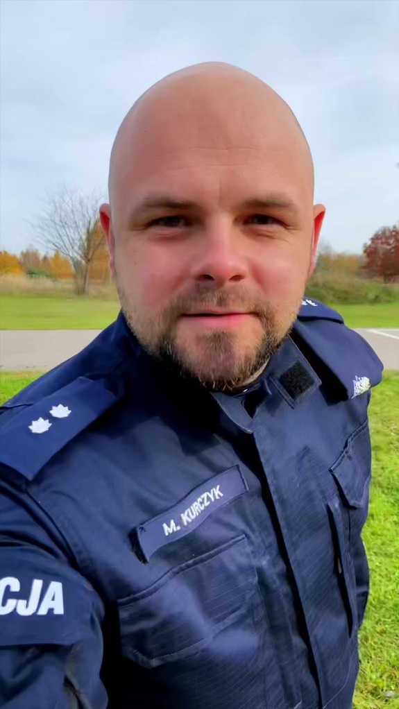 Policjant z brodą robi selfie.