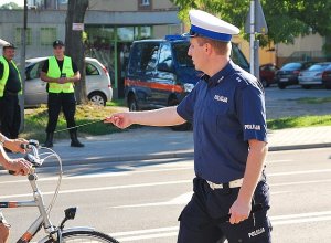 policjant daje opaskę odblaskową rowerzyscie