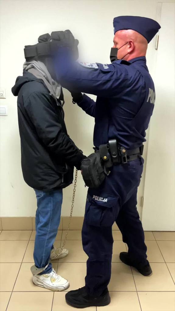 Policjant w maseczce na twarzy z zatrzymanym.