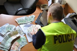 policjant zabezpiecza pieniądze na poczet kar