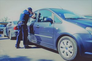 policjant sprawdza czy w samochodzie nie pozostało dziecko, osoba starsza czy zwierzę