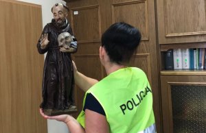 policjantka trzyma odzyskaną rzeźbę Św. Franciszka
