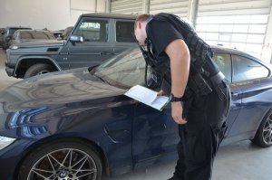 policjant prowadzi czynności przy odzyskanym samochodzie