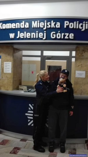 Chłopiec w kurtce policyjnej w objęciach policjantki. W recepcji komendy miejskiej policji w Jeleniej Górze.