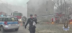 Policjanci i strażacy ewakuują ludzi z palącej się kamienicy