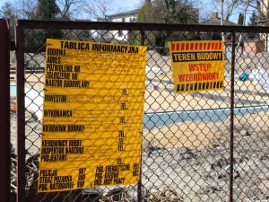 na siatce ogrodzeniowej żółta tablica informująca o budowie nowego posterunku Policji w Lesznie i tablica z napisem: Teren budowy, wstęp wzbroniony
