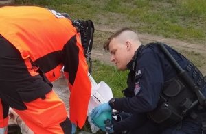 policjant z II Kompani Oddziału Prewencji Policji w Poznaniu z ratownikiem medycznym udzielają pomocy leżącemu mężczyźnie