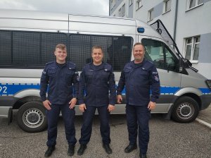 trzej policjanci z II Kompani Oddziału Prewencji Policji w Poznaniu w mundurach na tle radiowozu