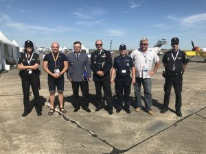 włoscy i polscy policjanci na płycie lotniska w tle samoloty i namioty wystawiennicze