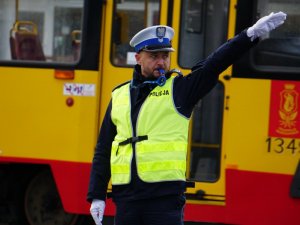 policjant z uniesioną ręką, w tle tramwaj