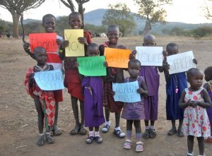 Dzieci z Tanzanii trzymają w rękach kartki na których napisali podziękowania dla policjantów i pracowników cywilnych