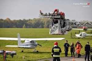 transport rannego spadochroniarza drabiną strażacką z dachu hangaru na tle osób biorących udział w ćwiczeniach sztabowych