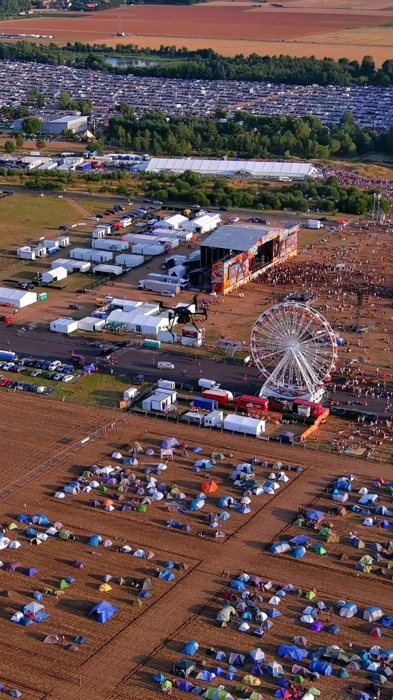 Dron unoszący się nad sceną i polem namiotowym festiwalu muzycznego.