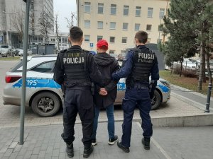 zatrzymany mężczyzna stoi pomiędzy dwoma policjantami