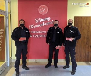 policjanci pozują do zdjęcia na tle szyldu stacji krwiodawstwa w Częstochowie