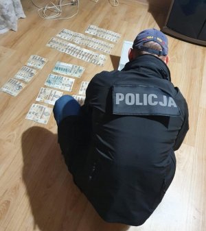 policjant zabezpiecza pieniądze leżące na podłodze