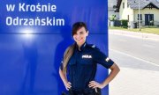Umundurowana policjantka stojąca przy banerze z napisem Komenda Powiatowa Policji w Krośnie Odrzańskim