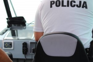 Policjant siedzi za sterem policyjnej łodzi