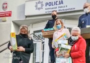 dwóch umundurowanych funkcjonariuszy oraz trzy kobiety stoją przed komisariatem policji z darami dla dzieci