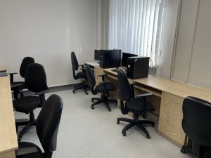 stanowiska komputerowe, przy których stoją krzesła obrotowe