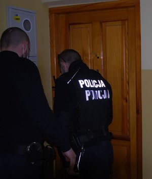policjanci przed drzwiami wejściowymi do mieszkania starszej kobiety