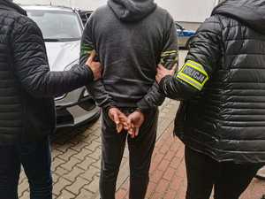 policjanci z zatrzymanym mężczyzną w kajdankach