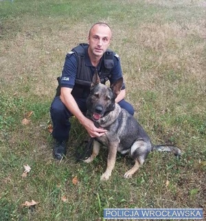 Zdjęcie przedstawia policjanta wraz z psem służbowym