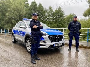Dwoje policjantów przy radiowozie na moście