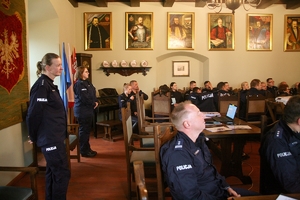 wnętrze pomieszczenia, policjanci siedzą przy stole słuchając wykładu
