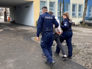 Policjanci prowadzą oszusta do komisariatu