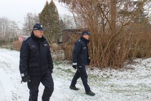 dwóch umundurowanych policjantów kontroluje tereny ogródków działkowych