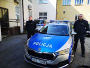 dwaj umundurowani policjanci pełniący służbę w PP Grębów stoją przy radiowozie