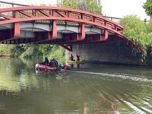 policjanci na łodziach na rzece pod mostem