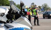 fragment policyjnego motocykla i dwaj umundurowani policjanci ruchu drogowego stojący na jezdni