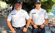 dwaj polscy policjanci w Chorwacji, w tle widoczna promenada nadmorska, drzewa i ludzie wypoczywający na plaży