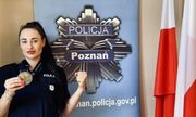 policjantka z medalem na szyi. z Tyłu widoczna grafika przedstawiająca policyjną odznakę z napisem Policja Poznań