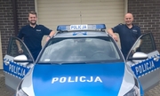 dwaj policjanci stoją przy radiowozie policyjnym