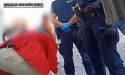 zatrzymany mężczyzna w czerwonej marynarce z policjantami