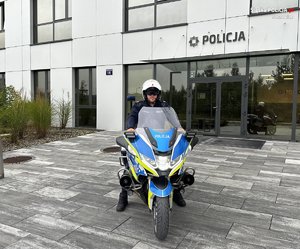 policjant na motocyklu przed budynkiem komendy policji