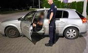 Umundurowany policjant stoi przy otwartych drzwiach auta, w którym siedzi kierowca
