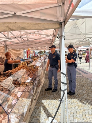 Dwójka włoskich umundurowanych policjantów stoi przy stoisku z żywnością